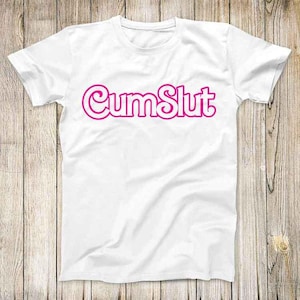 May include: White t-shirt featuring the pink text "CumSlut". The shirt has a crew neck and short sleeves. The graphic is centrally placed. The fabric appears to be soft and comfortable.
