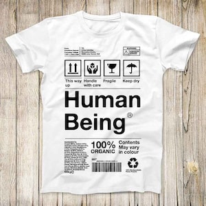May include: White t-shirt with a black and white graphic design that looks like a shipping label. The label says "Human Being 100% Organic" and has symbols for "This way up", "Handle with care", "Fragile", and "Keep dry".