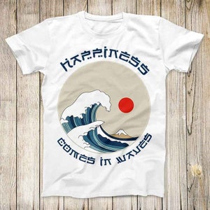 Peut inclure: T-shirt blanc avec un graphique d'une vague bleue et d'un soleil rouge. Le texte "Happiness comes in waves" est imprimé en cercle autour de la vague.