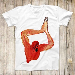 May include: White t-shirt featuring a red and orange illustration of a person in a yoga pose.