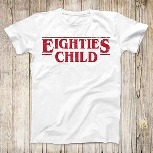 May include: White t-shirt with a red graphic that says "EIGHTIES CHILD" in a vintage style font.