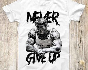 Pode incluir: Camiseta branca com uma ilustração em preto e branco de um homem musculoso com o texto "NEVER GIVE UP" em uma fonte que pinga.