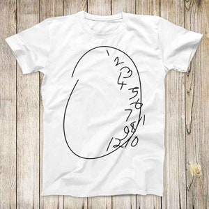 Puede incluir: Camiseta blanca con un diseño de reloj negro dibujado a mano. La esfera del reloj tiene forma ovalada con los números del 1 al 12 y una sola manecilla. El diseño está centrado en la parte delantera de la camiseta.