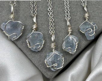 May include: Five silver necklaces with blue crystal pendants. Each pendant is wrapped in silver wire and hangs from a delicate silver chain.