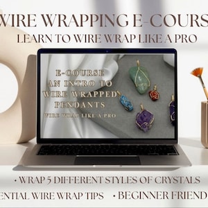 May include: A laptop computer screen displaying an online course titled "E-Course: An Intro to Wire Wrapped Pendants". The course teaches how to wire wrap crystals and includes five different styles of crystals. The text "Wire Wrap Like a Pro" is also on the screen. The laptop is on a white surface with a beige ceramic vase and paintbrushes.