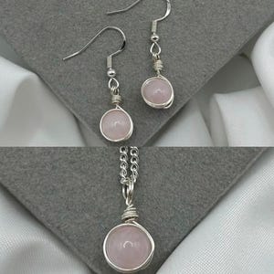 Puede incluir: Un conjunto de joyas de cuarzo rosa que incluye un collar y pendientes. El collar tiene una cadena de plata y un colgante de cuarzo rosa. Los pendientes son de plata con piedras de cuarzo rosa.