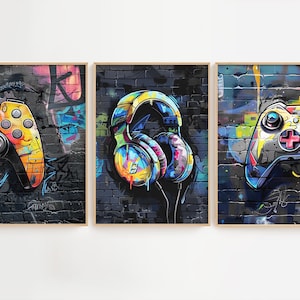 May include: Three framed prints with a graffiti-style background. The prints feature a colorful video game controller, a pair of headphones, and another colorful video game controller.