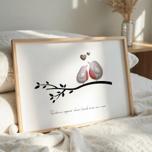 May include: A framed print with a black and white illustration of two birds perched on a branch. The birds are made of painted stones and are facing each other. The background is white and the text "Robins appear when loved ones are near" is printed below the birds.