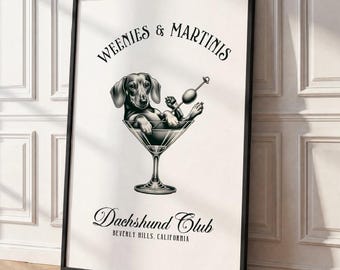 May include: A framed wall art print featuring a black and white illustration of a dachshund sitting inside a martini glass. The text reads Weenies & Martinis at the top and Dachshund Club Beverly Hills, California at the bottom.