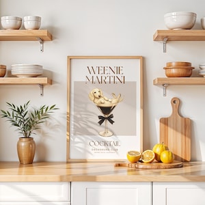 May include: A framed print featuring a dachshund dog in a martini glass, with the words "Weenie Martini" above and "Cocktail Dachshund Club" below. The artwork has a light brown and beige color scheme, with a black bow tie on the glass.
