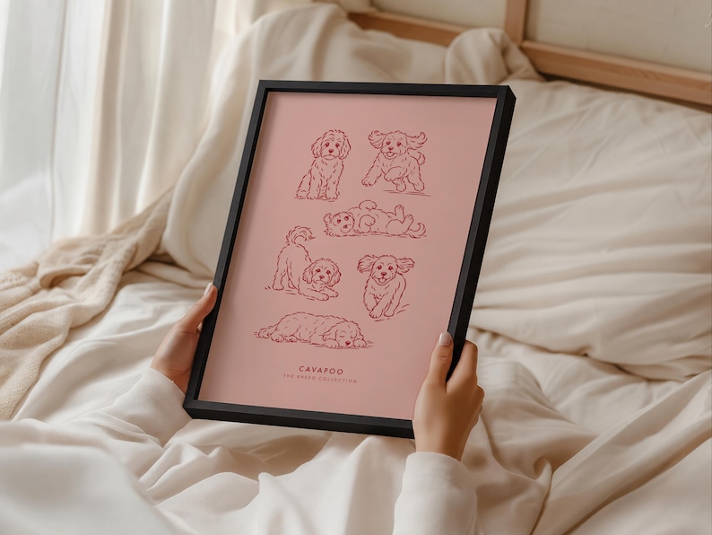 May include: A black framed print featuring six dark red line art illustrations of Cavapoo dogs in various poses on a dusty rose background. The text at the bottom reads CAVAPOO THE BREED COLLECTION in a simple, clean, sans-serif font.