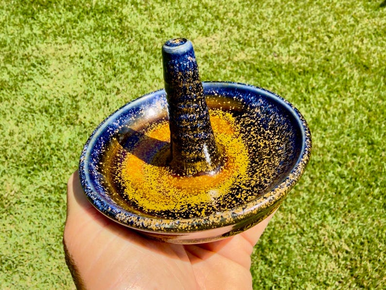 Handmade ceramic ring holder featuring flowing glaze and natural color variation, pottery jewelry holder with glossy surface and unique finish.