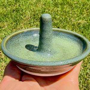 Handmade ceramic ring holder featuring flowing glaze and natural color variation, pottery jewelry holder with glossy surface and unique finish.