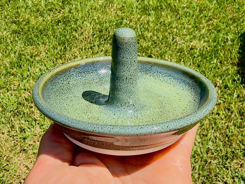Handmade ceramic ring holder featuring flowing glaze and natural color variation, pottery jewelry holder with glossy surface and unique finish.