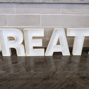 May include: White, freestanding letters spelling out the word "CREATE" on a tiled floor.