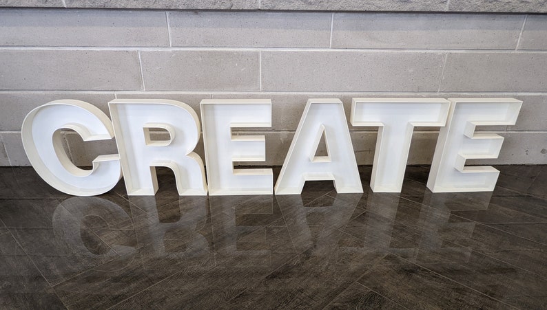 May include: White, freestanding letters spelling out the word "CREATE" on a tiled floor.