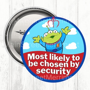 May include: A round pin-back button featuring a green three-eyed alien character in a blue space suit with a red claw above its head. The background is light blue with white clouds. The text reads Most likely to be chosen by security.