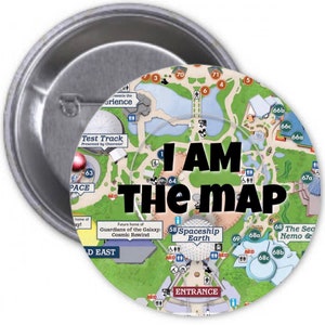 May include: A round button with a map of a theme park. The map is green and blue with various attractions labeled. The text "I AM THE MAP" is in large black letters in the center of the button.