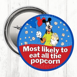 May include: A circular badge featuring Goofy holding popcorn and balloons. The badge has the text "Most likely to eat all the popcorn" in white on a red background, with a blue border.