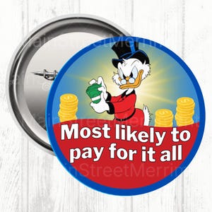 May include: A round button featuring Scrooge McDuck holding money, with stacks of gold coins. The text "Most likely to pay for it all" is displayed on a red banner. The button has a blue border and a silver pin back.