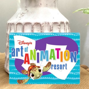 Pode incluir: Uma placa azul e roxa com o texto "Disney's art of ANIMATION resort" em letras coloridas. Um desenho animado de uma tartaruga marinha com uma expressão feliz está no centro da placa.
