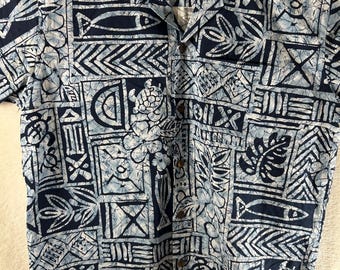 May include: A short-sleeved button-down shirt with a blue and white batik-style pattern. The design includes fish, turtles, and floral motifs. The shirt has a collar and a label that reads "Favant".