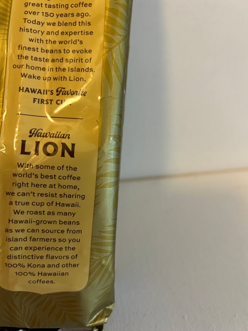 Pu&ograve; includere: Un sacchetto di caff&egrave; dorato e marrone con un logo di leone e il testo "Hawaiian Lion". Il sacchetto presenta una descrizione del caff&egrave;, indicando che &egrave; fatto con alcuni dei migliori caff&egrave; del mondo, tostati a partire da chicchi coltivati alle Hawaii. Il testo menziona anche che il caff&egrave; &egrave; 100% Kona e altri caff&egrave; 100% hawaiani.