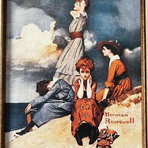 May include: A vintage framed print of a painting by Norman Rockwell depicting four women on a beach. The women are wearing dresses and hats. The painting is set against a backdrop of a cloudy sky and ocean.