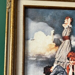 May include: A framed vintage print of a painting depicting five women standing on a cloud in a sky with a dramatic, stormy background. The women are dressed in clothing from the early 1900s. The print is framed in a gold-colored frame.
