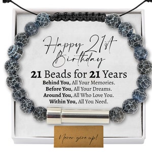 Op de afbeelding: Een armband van zwarte en witte kralen met een zilveren bedel en een kaart met de tekst "Happy 21st Birthday 21 Beads for 21 Years Behind You, All Your Memories. Before You, All Your Dreams. Around You, All Who Love You. Within You, All You Need. Never give up!"