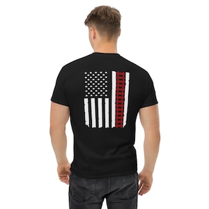 May include: Black t-shirt with a white American flag design on the back. The flag has a red railroad track design running down the right side.