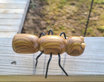 Escultura de hormiga hecha con torno de madera y patas de alambre
