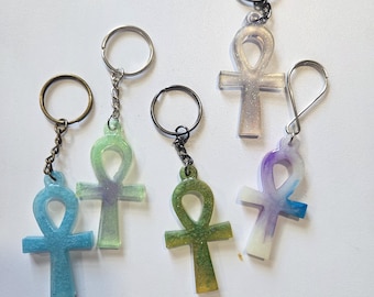 Pode incluir: Cinco porta-chaves em forma de ankh feitos de resina, cada um com um anel e corrente de metal. As cores incluem azul com purpurina, verde claro com roxo, uma mistura de verde escuro e amarelo, branco translúcido com purpurina e um redemoinho azul e roxo.