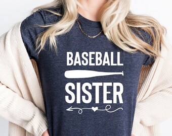 May include: A heather midnight navy t-shirt with the text "BASEBALL SISTER" in white with a white baseball bat graphic and a white arrow with a heart.