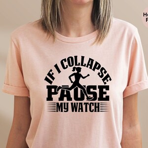 May include: A heather peach t-shirt with a black graphic that says "If I Collapse Pause My Watch" with a silhouette of a woman running.