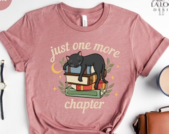 Puede incluir: Camiseta de color malva heather con un gato negro durmiendo sobre una pila de libros. El texto "just one more chapter" está impreso en la camiseta.