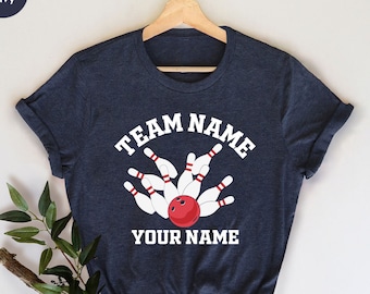 May include: Heather navy blue t-shirt with white text that says "TEAM NAME" in an arc above a bowling ball and pins. The text "YOUR NAME" is below the bowling ball and pins.