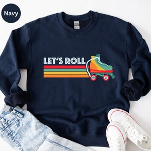 May include: Navy blue sweatshirt with a retro-style graphic of a roller skate and the text "Let's Roll" in white. The graphic features colorful stripes and a yellow, orange, and green roller skate.