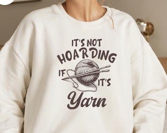 May include: White sweatshirt with a brown graphic that says "It's not hoarding if it's yarn" with a drawing of a ball of yarn and knitting needles.