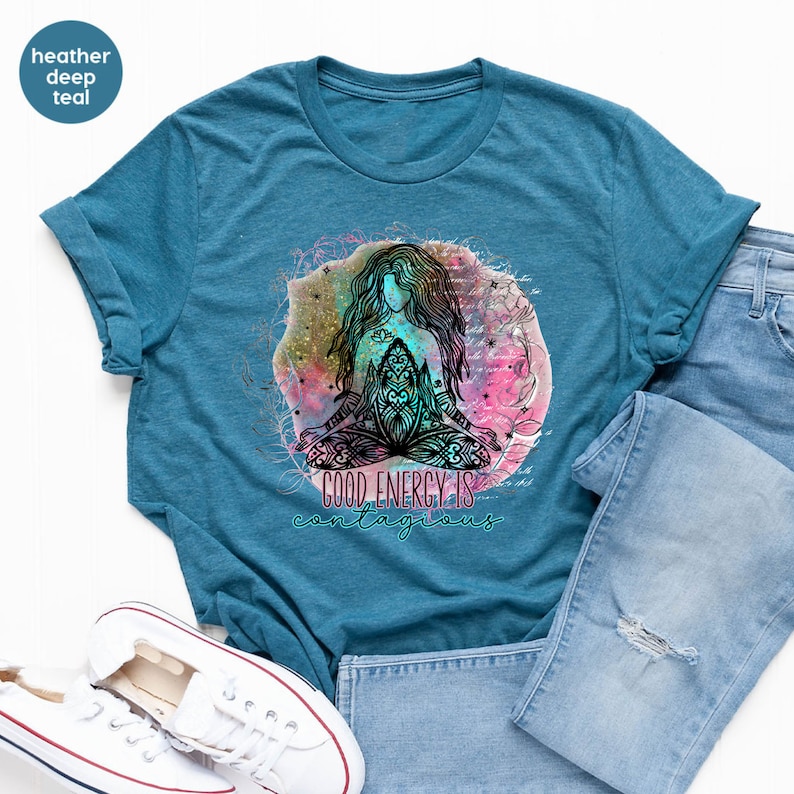 Peut inclure: T-shirt bleu sarcelle chin&eacute; avec un motif d'une femme m&eacute;ditant en position du lotus, entour&eacute;e d'un design aquarelle color&eacute;. Le texte "GOOD ENERGY IS contagious" est en dessous. Le t-shirt est associ&eacute; &agrave; un jean bleu et des baskets blanches.