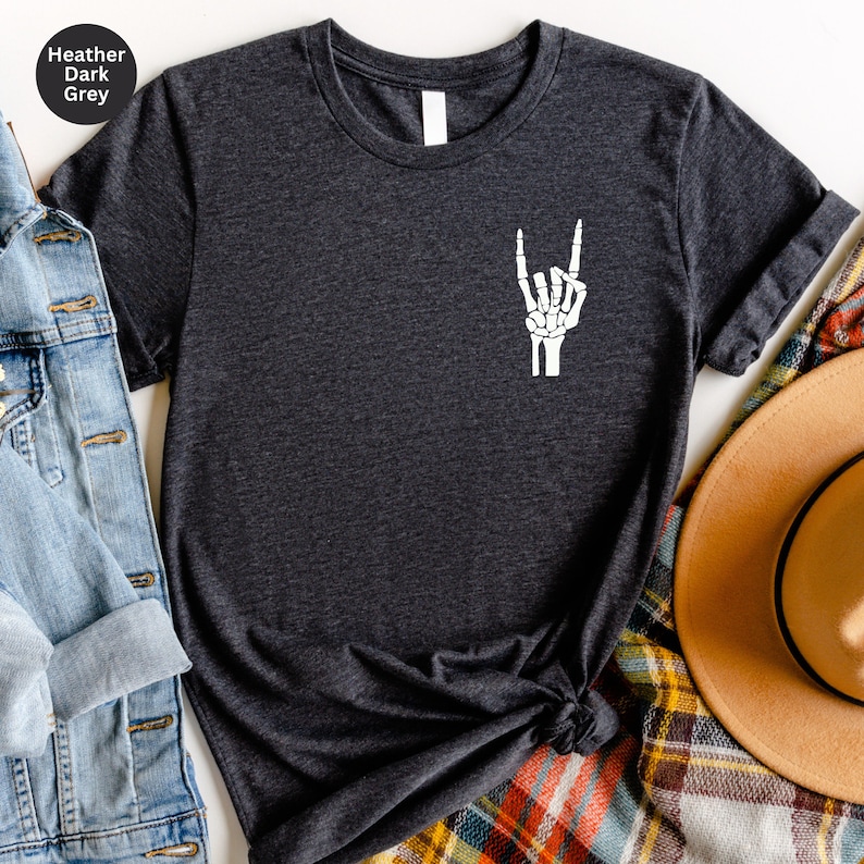 May include: Heather dark grey t-shirt with a white skeleton hand graphic in the rock and roll gesture. The shirt has a crew neck and short sleeves. The text "Heather Dark Grey" is in a circle in the upper left corner.