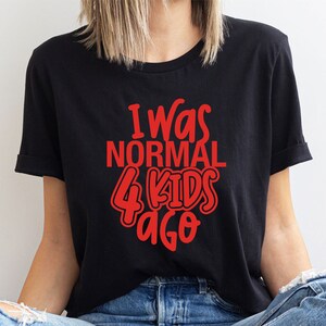 Może przedstawiać: Czarny t-shirt z czerwonym napisem "I Was NORMAL 4 KIDS Ago". Koszulka z kr&oacute;tkim rękawem ma okrągły dekolt. Tekst jest w zabawnej, zaokrąglonej czcionce. Wykonana z miękkiego materiału.