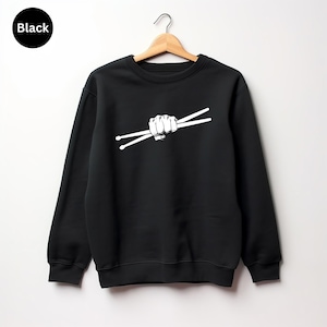 May include: Black sweatshirt with a white graphic of a fist holding drumsticks.