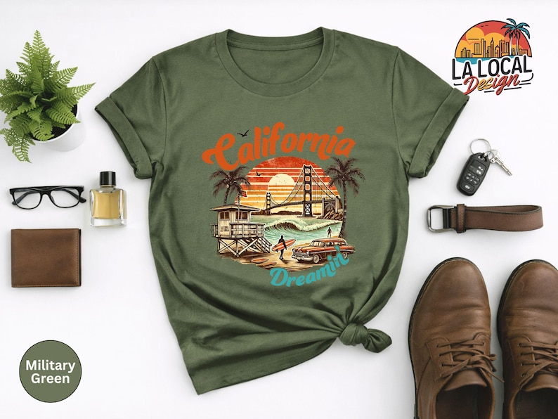 May include: Military green t-shirt featuring a California Dreamin' graphic with a sunset, palm trees, and the Golden Gate Bridge. The shirt is styled with accessories like glasses, a wallet, and brown leather shoes.