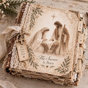 May include: A square scrapbook featuring a sepia-toned nativity scene with Mary, Joseph, and the infant Jesus. The cover includes the text The Savior Is Born and a hanging tag reading His Story Our Hope. It is decorated with lace, fabric ribbons, and side tabs labelled faith, joy, peace, and Christmas.