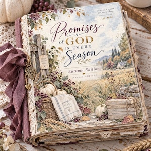 May include: A hardcover book titled Promises of God in Every Season Autumn Edition with a decorative spine featuring a dark purple fabric ribbon, a metal leaf charm, and a heart charm. The cover displays a landscape illustration with pumpkins.