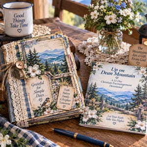 May include: A devotional book titled Up on Dean Mountain and a matching scrapbook featuring mountain landscapes, pine trees, and white flowers. The scrapbook includes lace trim, a wooden button, and tags with the text Grateful for Simple Days.