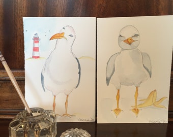 Seagulls. Two unique original hand painted watercolor paintings. A seagull with lighthouse. A thick seagull with banana peel.