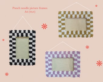 May include: Three punch needle picture frames with checkerboard patterns in black and white, gold and white, and lavender and white. Each frame is A6 size (15.24 x 10.16 cm) and hangs from a white string. The text "Punch needle picture frames A6 (6x4)" is at the top.