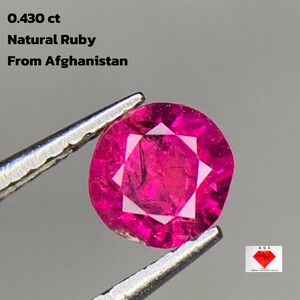 Op de afbeelding: Een natuurlijke robijn edelsteen uit Afghanistan, vastgehouden door een pincet. De edelsteen heeft een dieproze kleur, met een facetgeslepen slijpvorm. De tekst luidt: "0.430 ct Natural Ruby From Afghanistan."